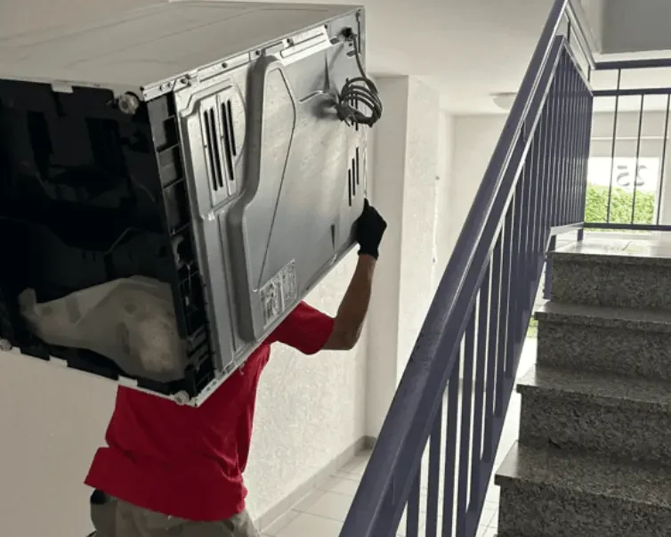 Mann beim Heraustragen einer Waschmaschine aus dem Privathaushalt - R&B Dienstleistungen Darmstadt - Entrümpelung von Haushalten in Hessen